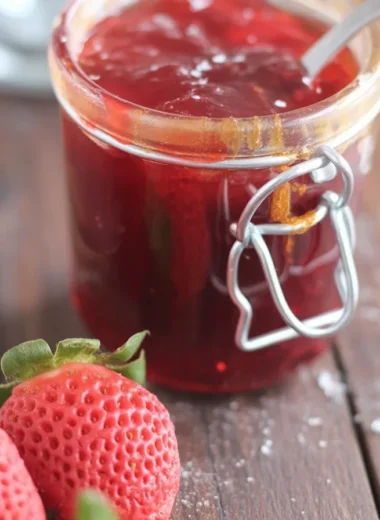 Homemade jam recipe with strawberries, sugar, and lemon juice boiled in a saucepan.