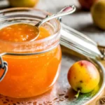 Homemade crab apple jam in glass jars with fresh crab apples and cinnamon stick on rustic wooden table