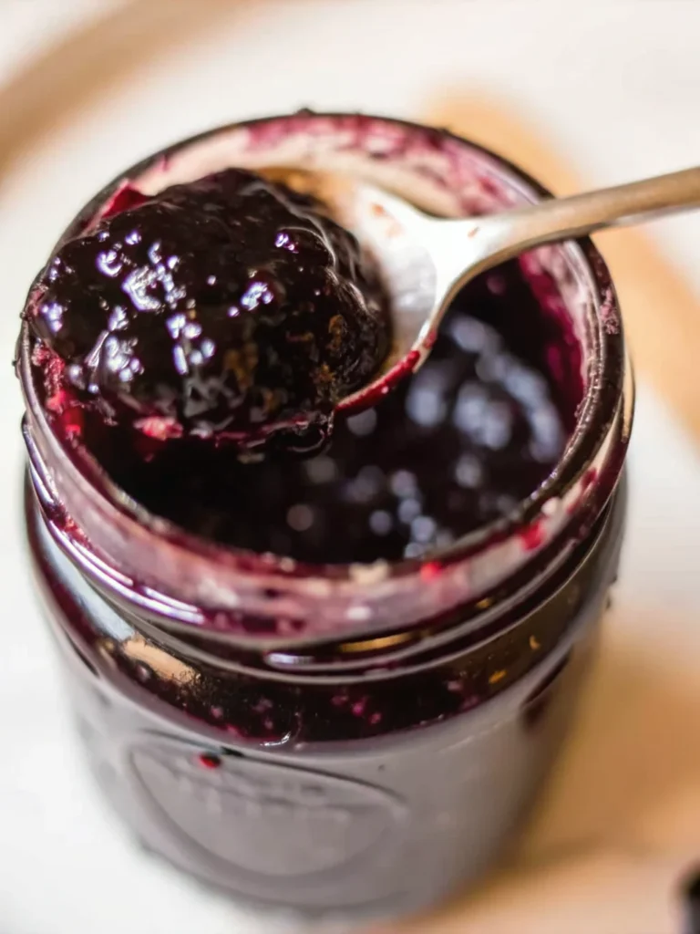 Homemade cherry jam recipe in glass jars with fresh cherries and wooden spoon on rustic kitchen counter