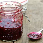 Homemade mixed berry jam recipe in glass jars with fresh strawberries, blueberries, and blackberries on rustic wooden table