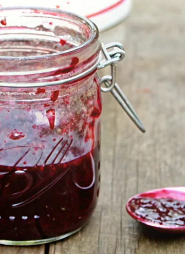 Homemade mixed berry jam recipe in glass jars with fresh strawberries, blueberries, and blackberries on rustic wooden table