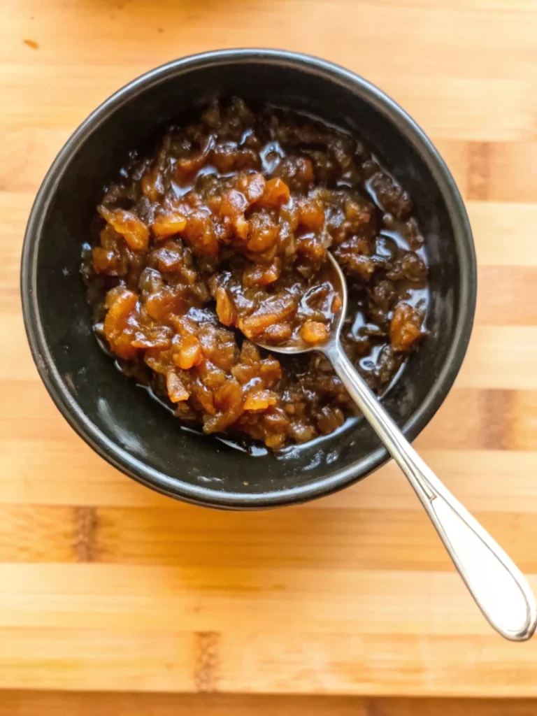 Homemade balsamic onion jam in glass bowl with wooden spoon showing rich caramelized color and jam-like consistency