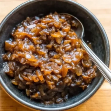 Homemade balsamic onion jam in glass bowl with wooden spoon showing rich caramelized color and jam-like consistency