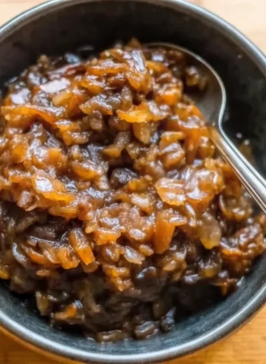 Homemade balsamic onion jam in glass bowl with wooden spoon showing rich caramelized color and jam-like consistency