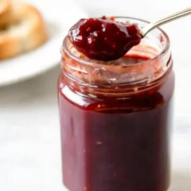 Homemade grape jam recipe in glass jars with fresh grapes and ingredients on wooden table