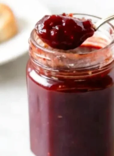 Homemade grape jam recipe in glass jars with fresh grapes and ingredients on wooden table