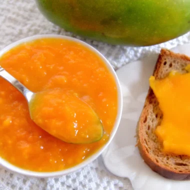 Fresh homemade mango jam in glass jar with golden color and smooth texture, made from ripe mangoes following easy mango jam recipe