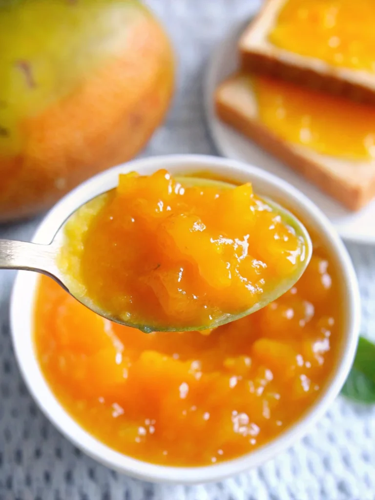 Fresh homemade mango jam in glass jar with golden color and smooth texture, made from ripe mangoes following easy mango jam recipe