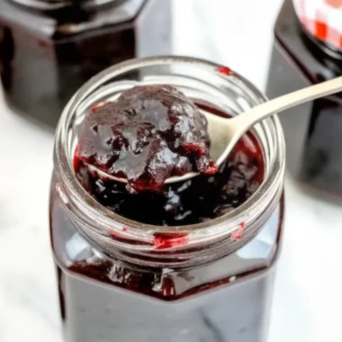 Homemade black currant jam recipe in glass jar with fresh black currants and ingredients on wooden table