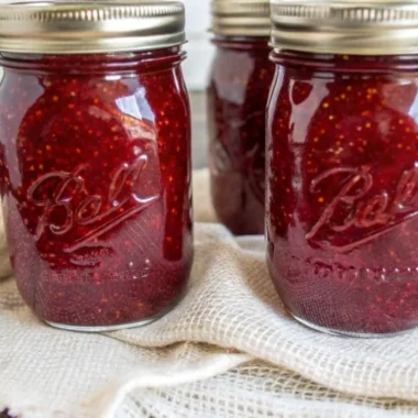 Easy homemade strawberry jam canning recipe showing fresh crushed strawberries, sugar, and pectin ingredients with mason jars and canning supplies for beginners