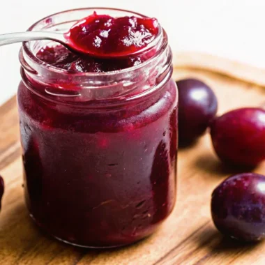 Fresh homemade plum jam without pectin in glass jars with golden color and chunky texture, featuring jam recipe ingredients including whole plums and lemon