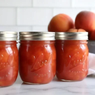 Homemade nectarine jam in glass jar with fresh nectarines and golden color showing perfect consistency for canning and preserving