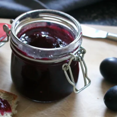 Homemade damson jam in glass jars with fresh damson plums, traditional British preserve recipe with deep purple color
