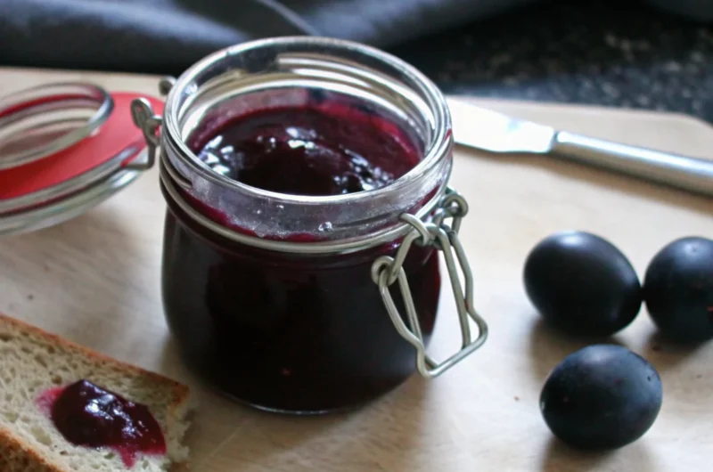 Homemade damson jam in glass jars with fresh damson plums, traditional British preserve recipe with deep purple color